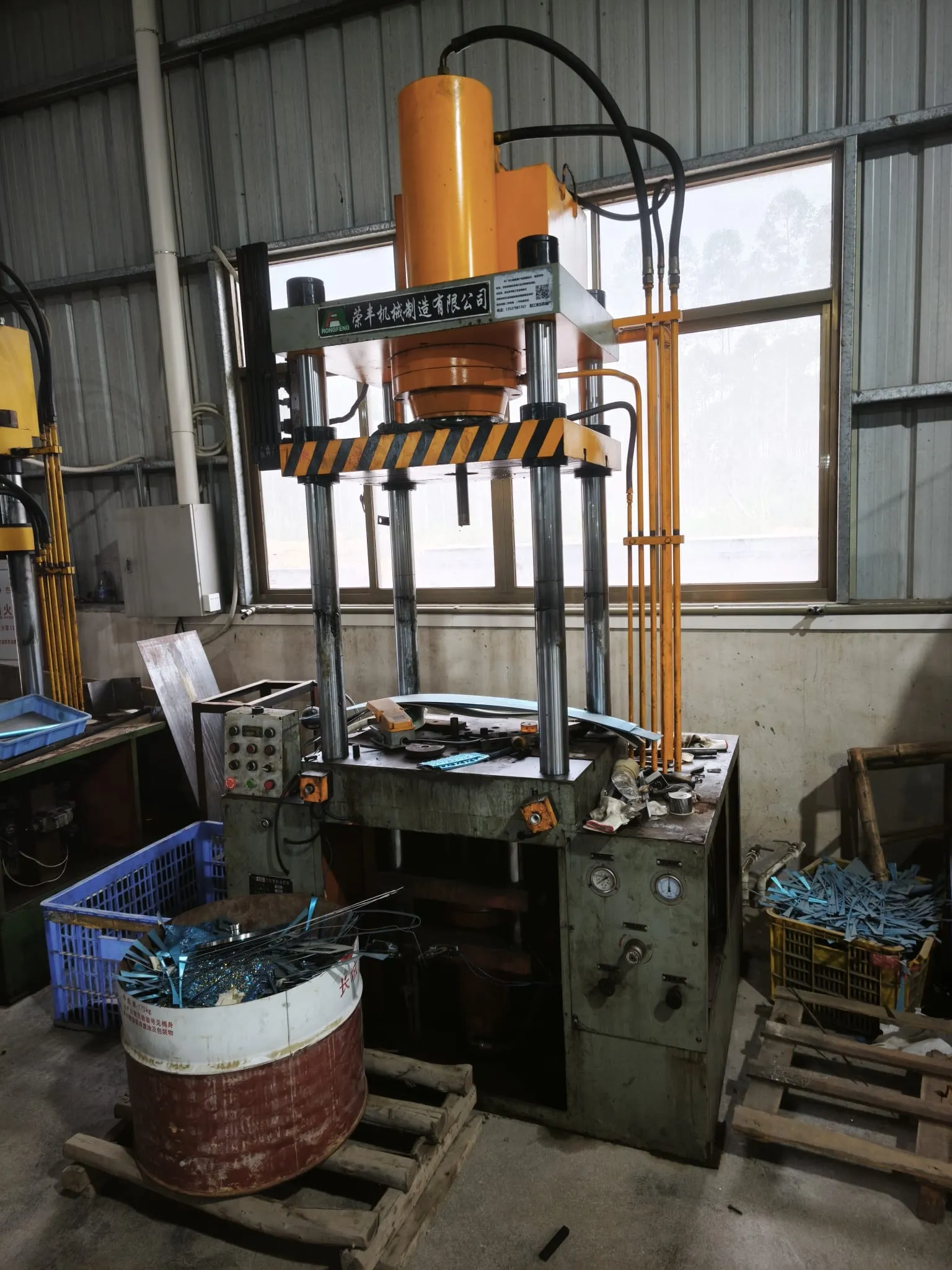 Four-column hydraulic press with formed steel parts in a crate