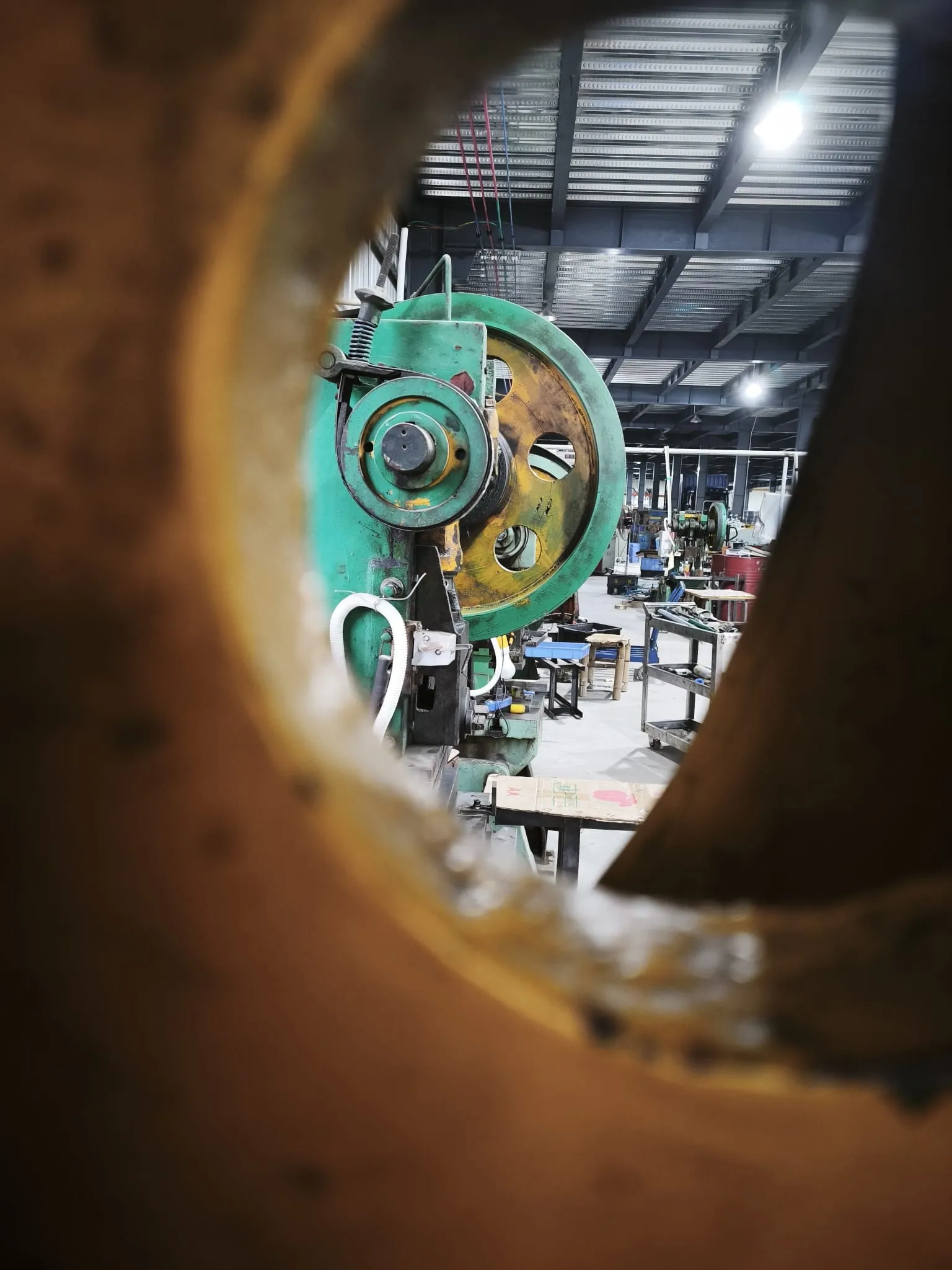 Press flywheels seen through the opening of another press frame